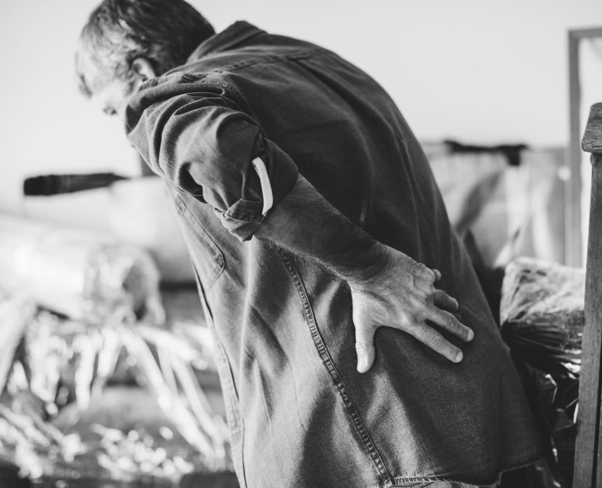 black and white image of man holding back in pain