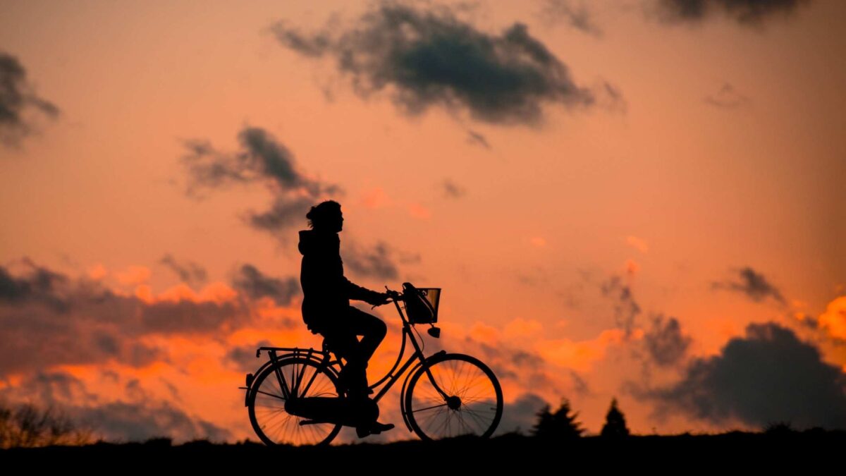 silhouette of person riding bike at sunset