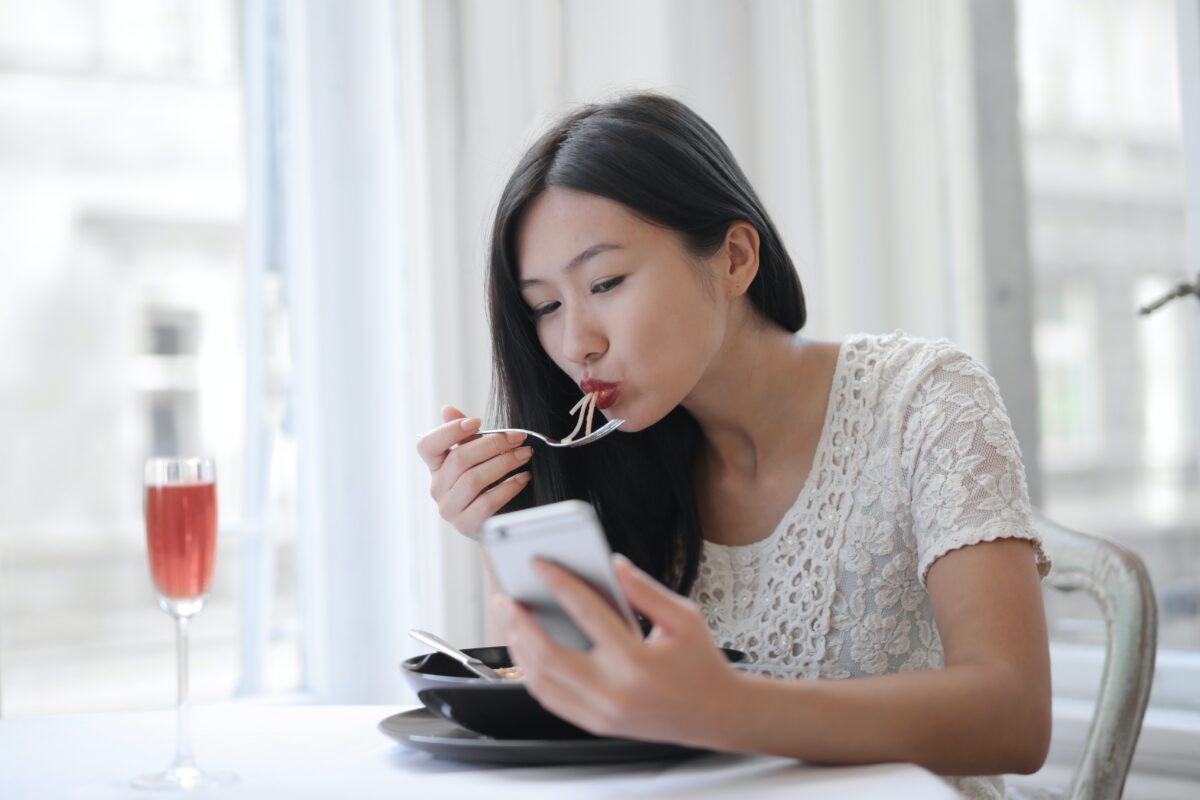 woman eating while looking at phone
