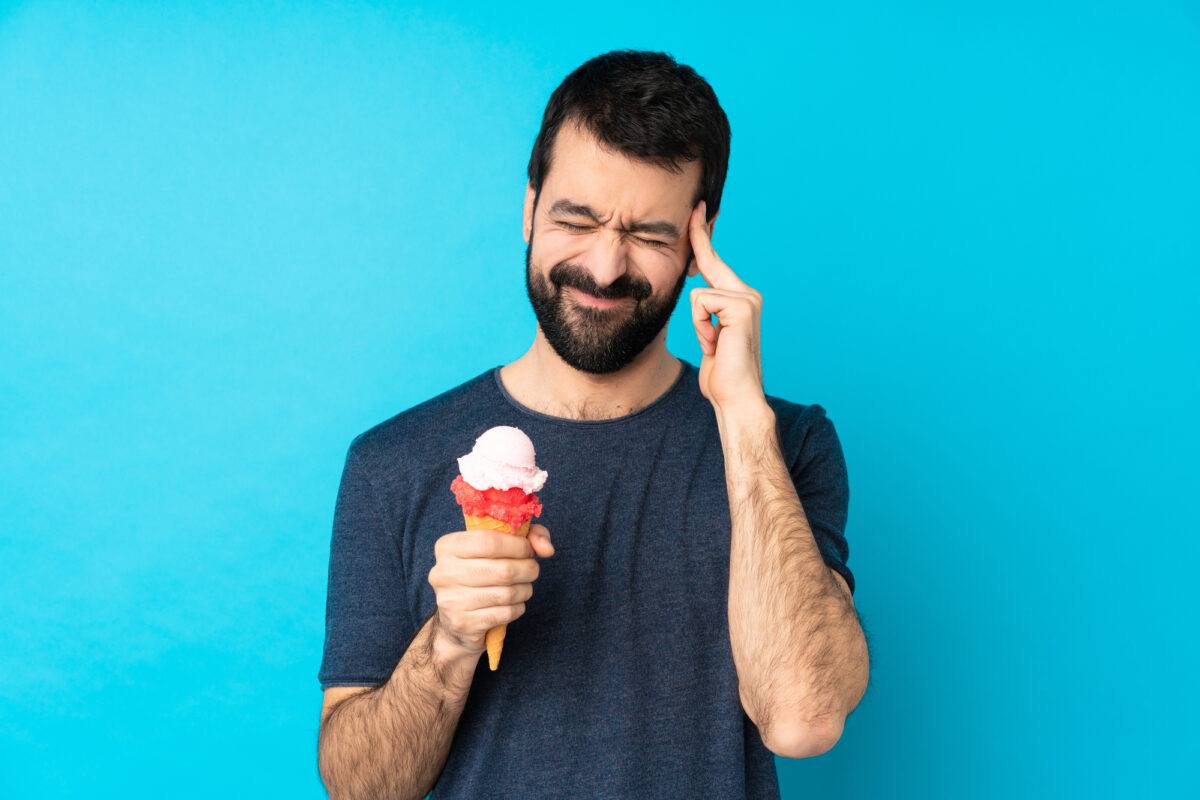 man with ice cream cone holding head in pain