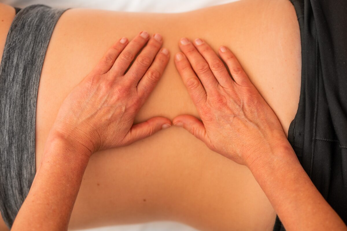 massage therapist's hands on patient's back
