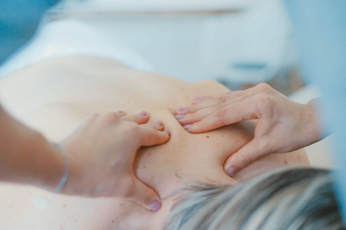 massage therapist's hands on patient's shoulders