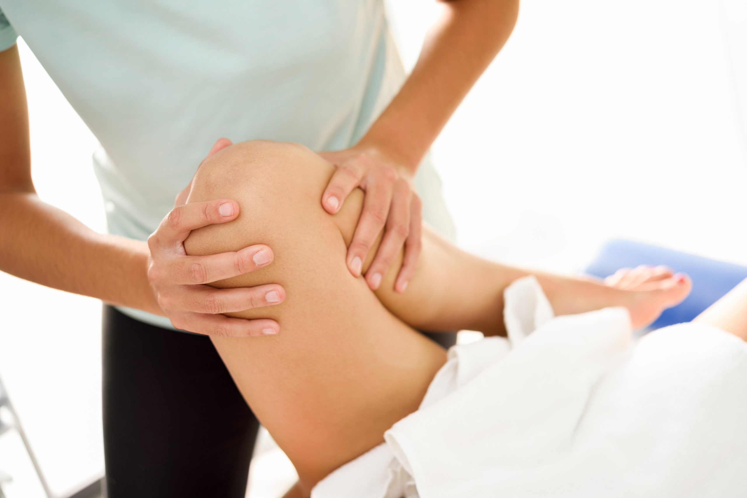 a professional providing a medical massage to relieve knee pain on woman