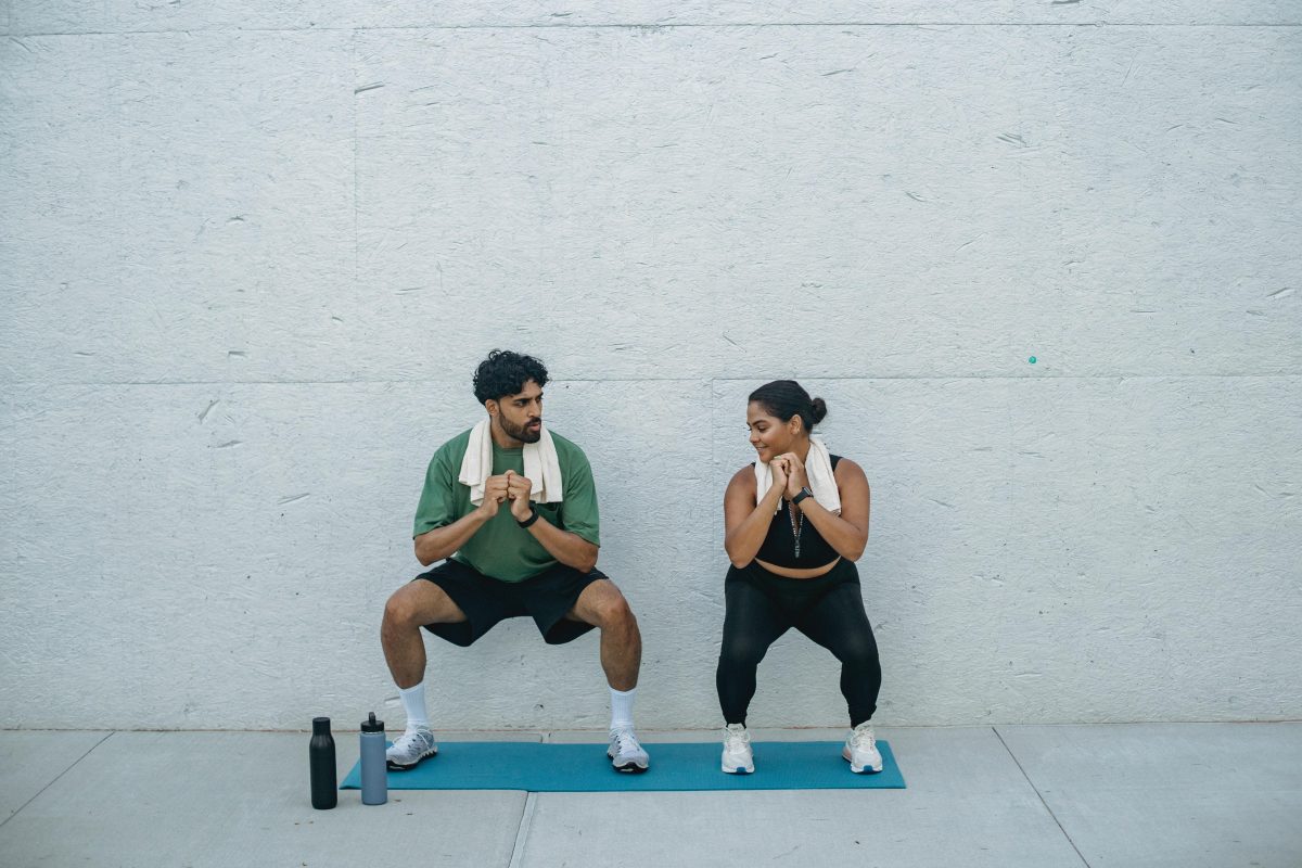 A man and woman do squats, an intense but low impact cardio exercise.