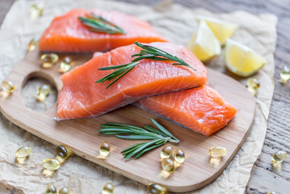 salmon on cutting board surrounded by omega-3 supplements