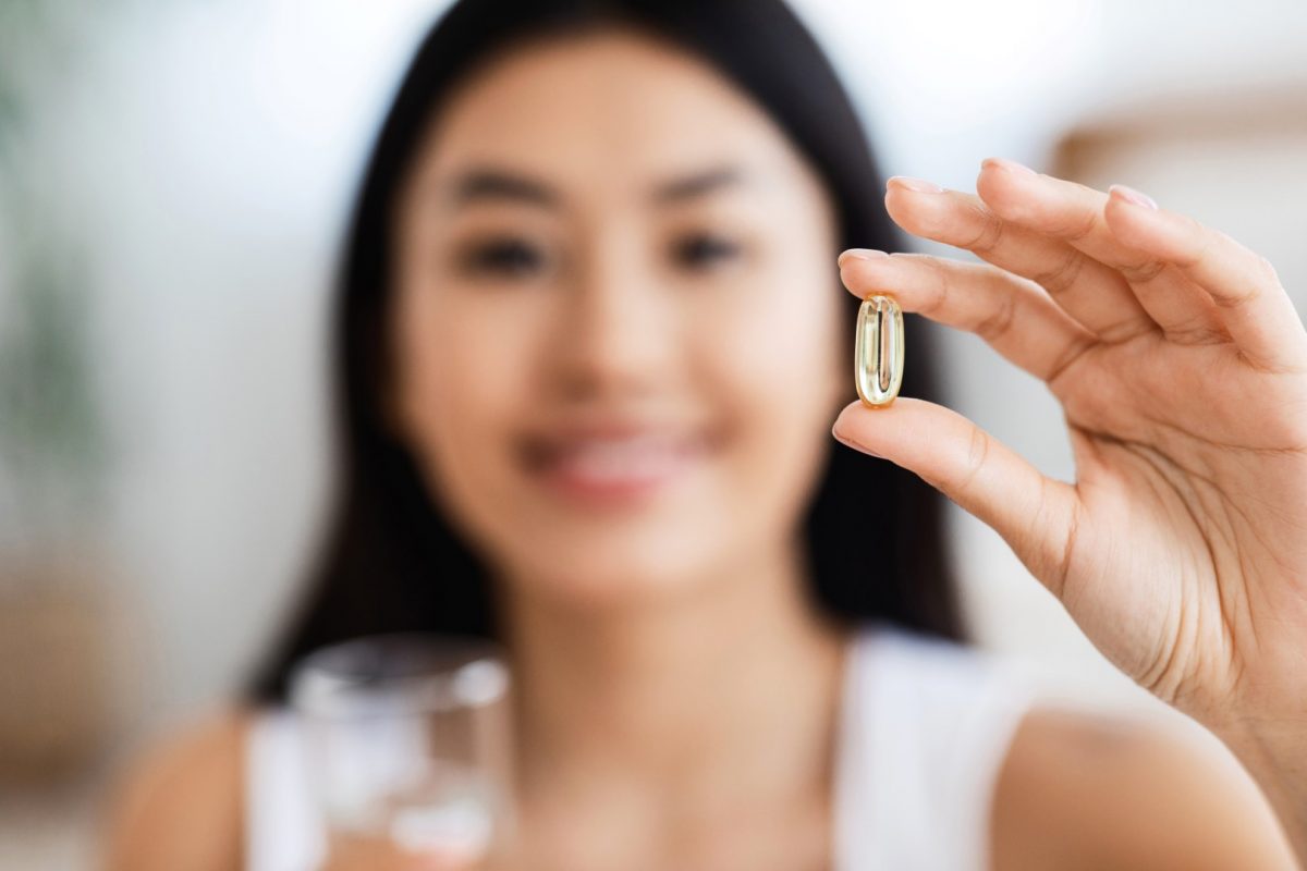 Woman holding up one supplement capsule