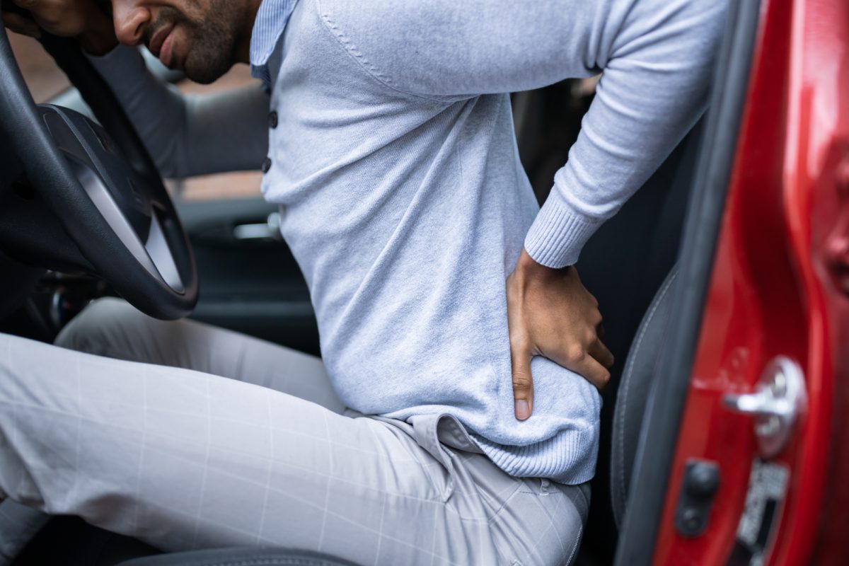 man sitting in car with back pain