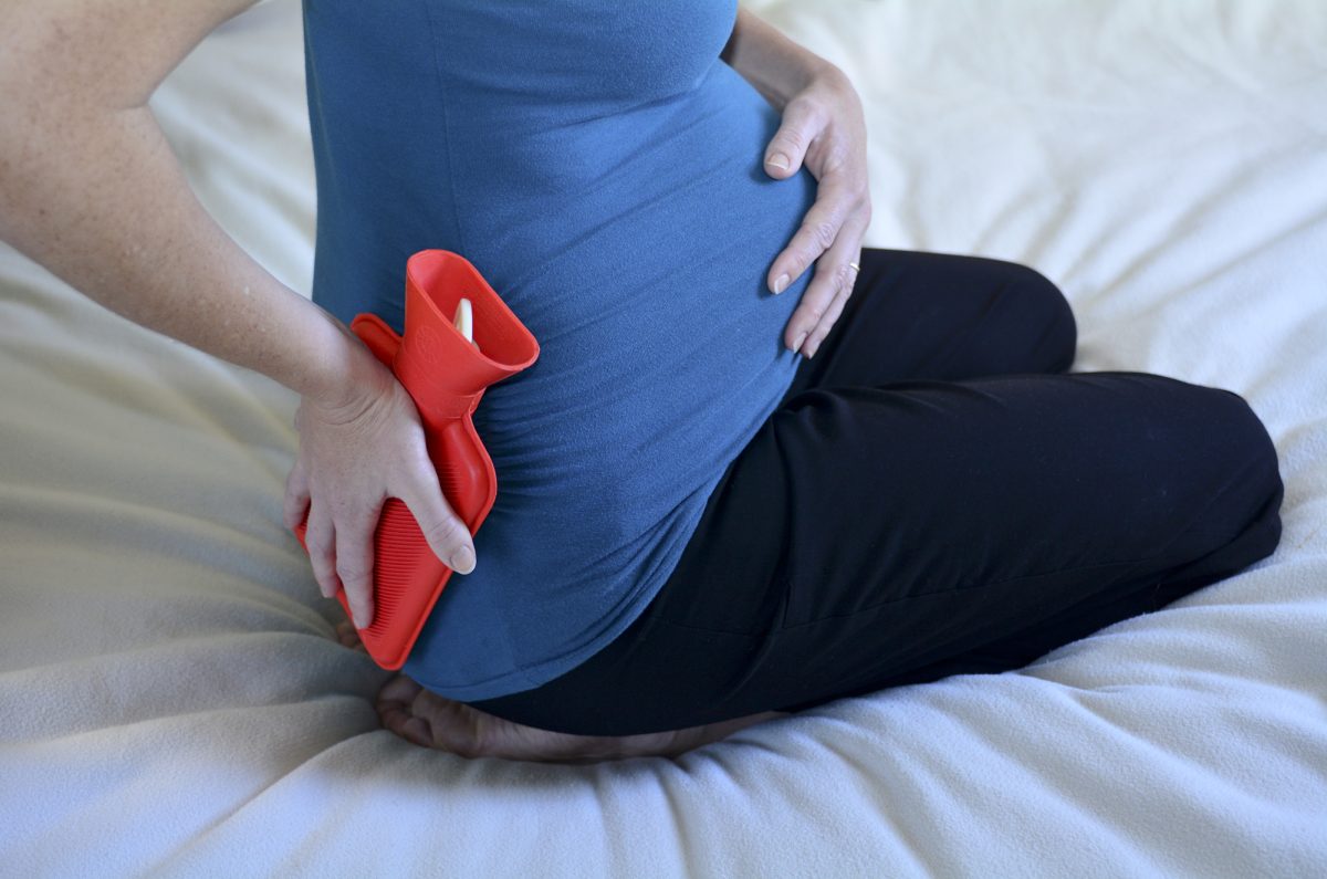 pregnant woman holding hot water bottle to lower back