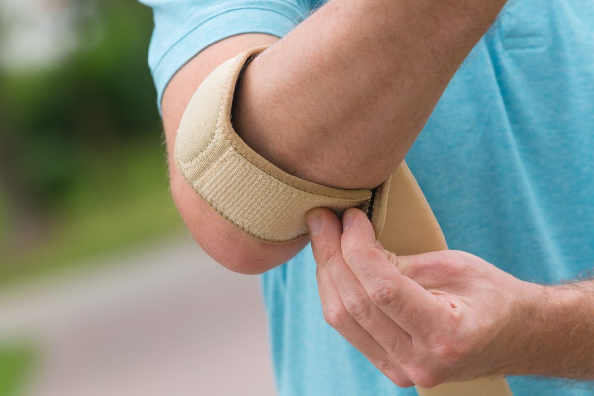close up of man putting on brace to fix tennis elbow