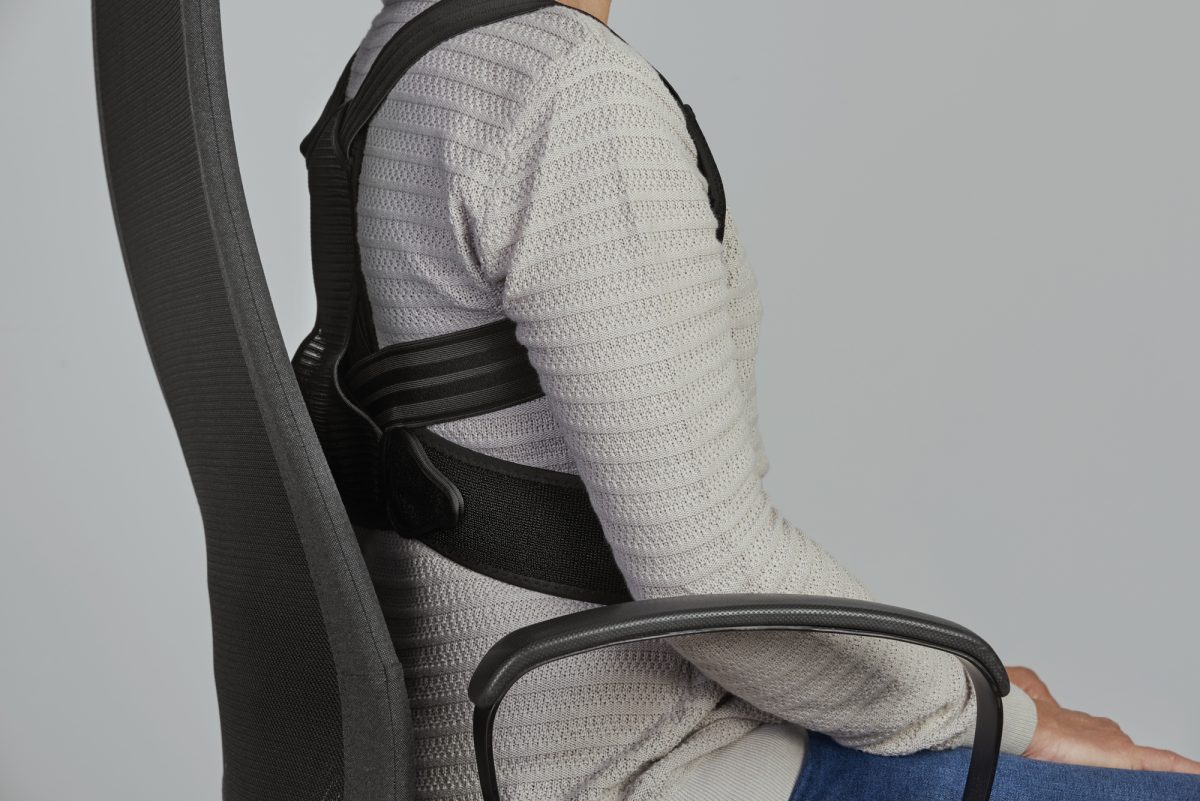closeup of person wearing posture corrector while sitting in office chair