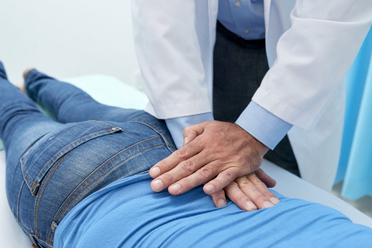 chiropractor making adjustment to patient's lower back