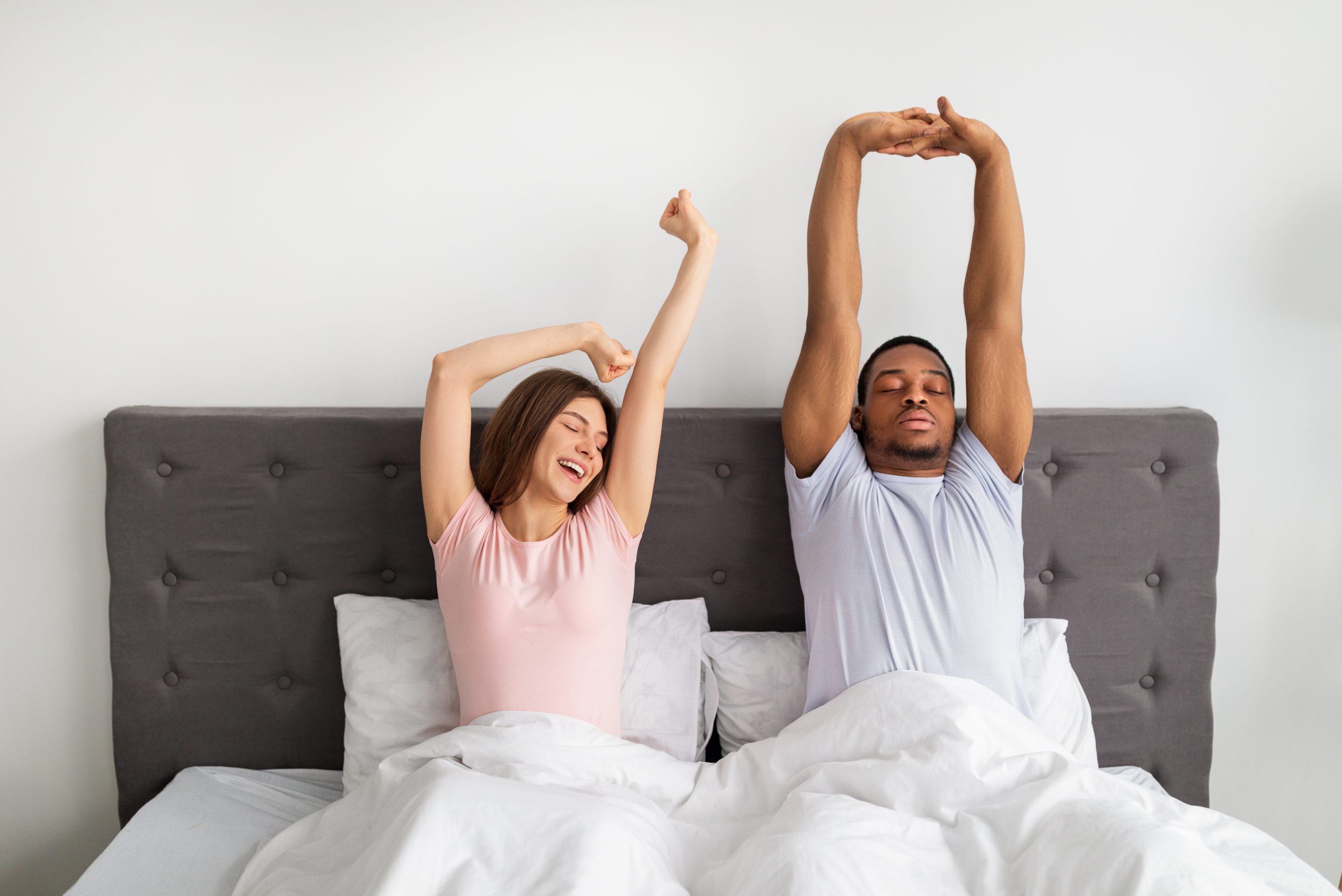 couple stretching while sitting in bed